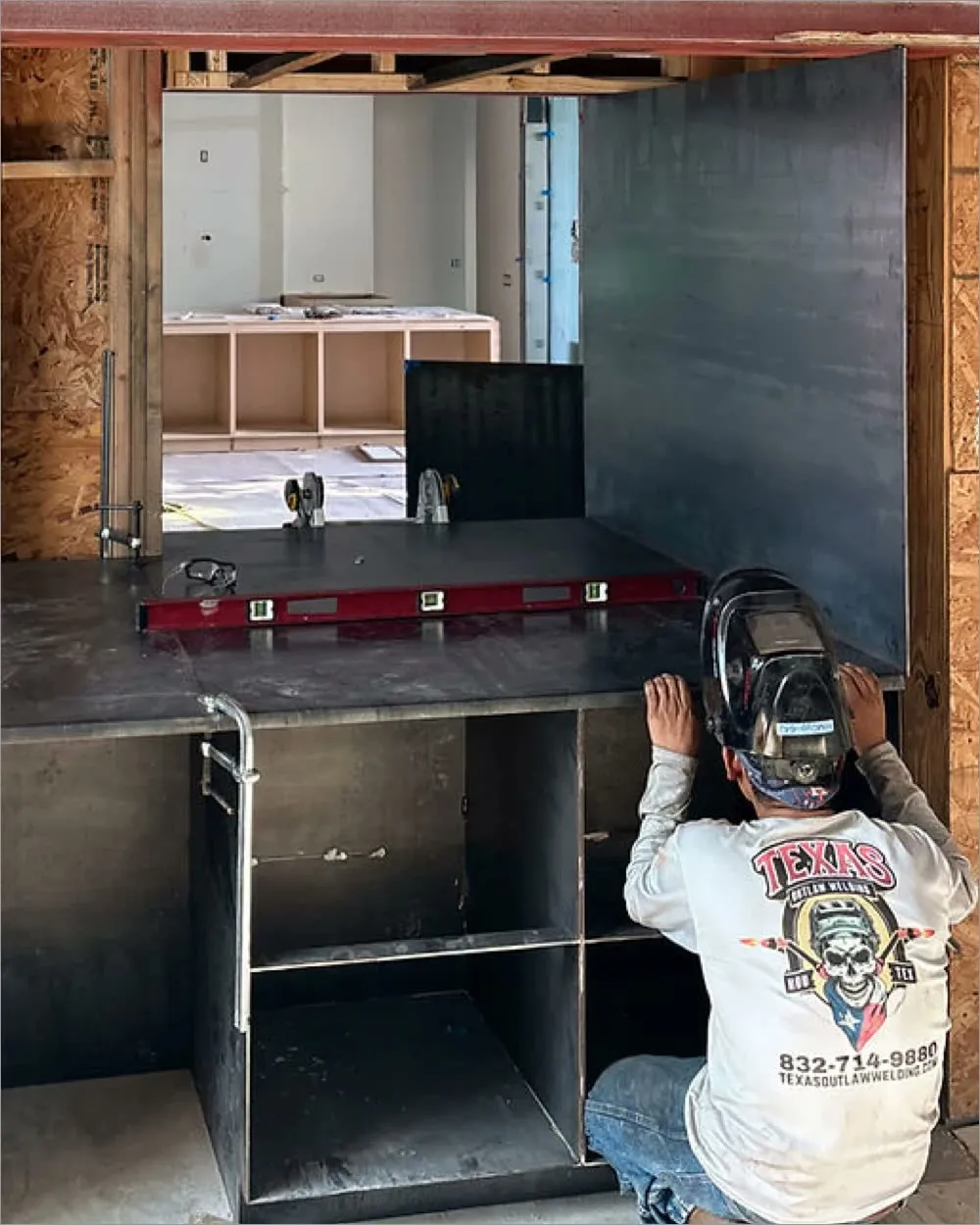A Texas Outlaw Welding fabricator levelling a steel counter assembly on site during a buildout