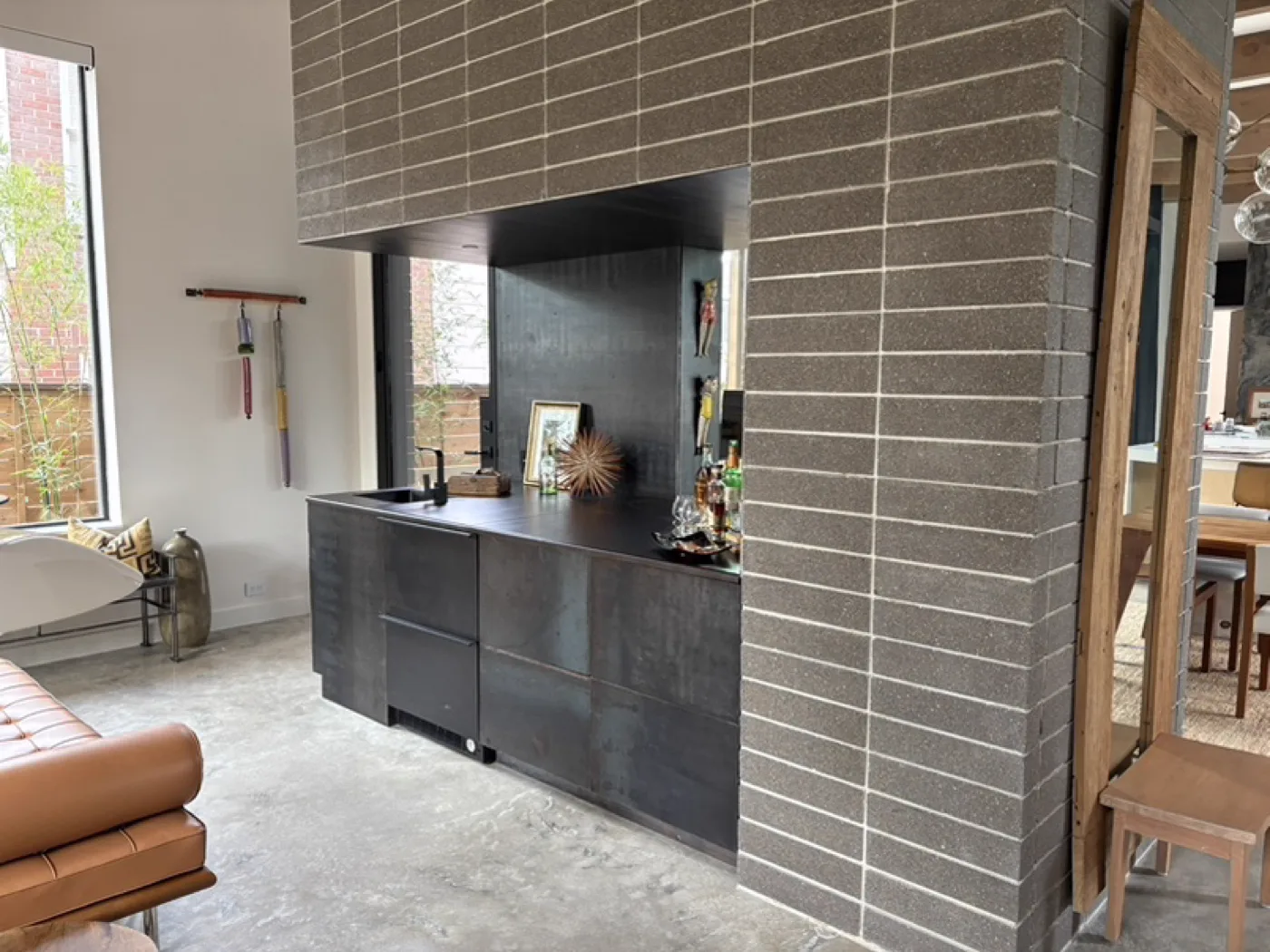 Blackened steel bar unit and steel-faced cabinetry set into a masonry opening at the 2510 Dryden residence