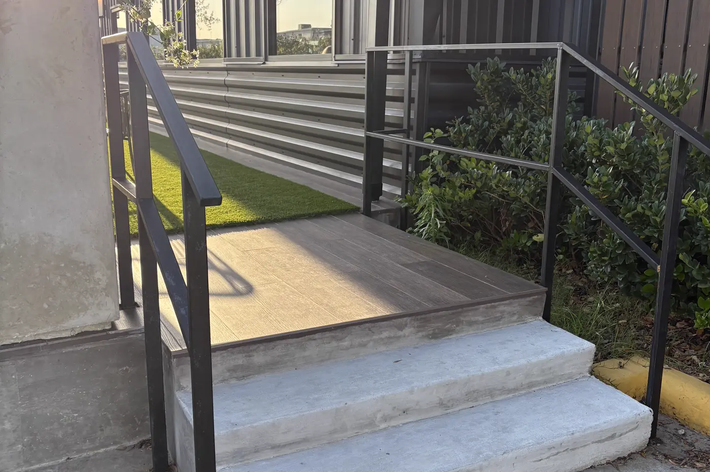 Powder-coated steel handrail and guardrail at a commercial entry stair