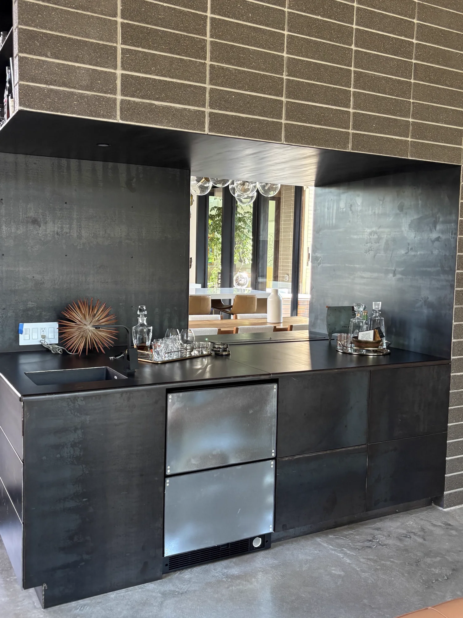 Blackened steel bar with a pass-through opening set into a masonry wall