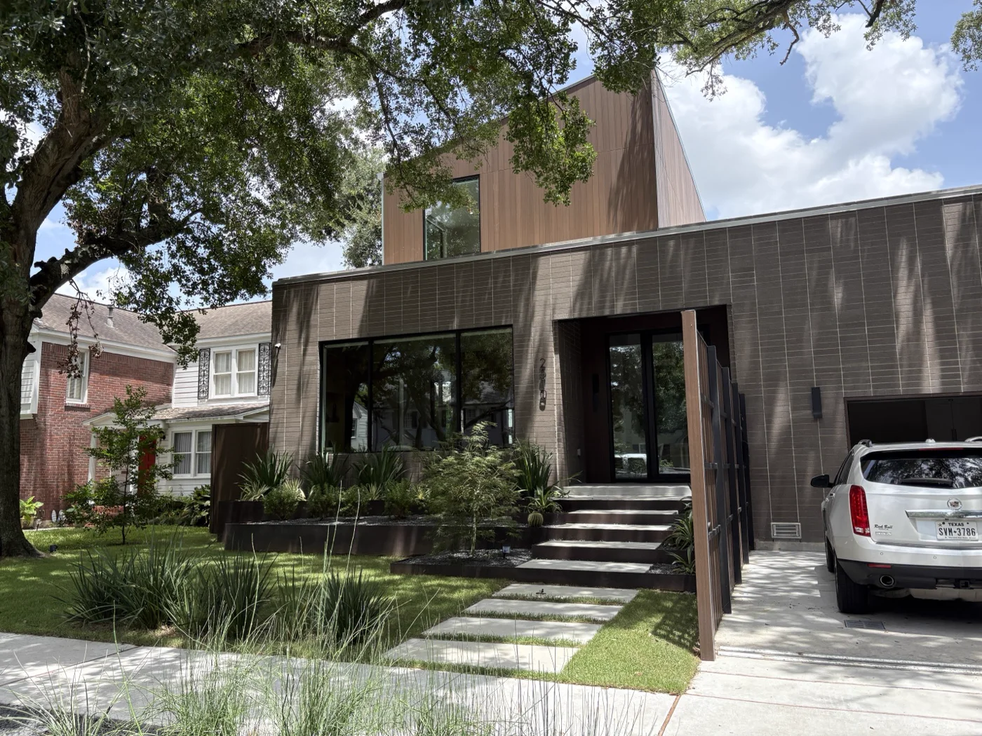 Street elevation of a modern Houston residence with steel entry screening and steel-edged planters
