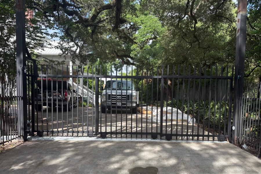 Closed steel picket sliding gate on its track across a residential driveway