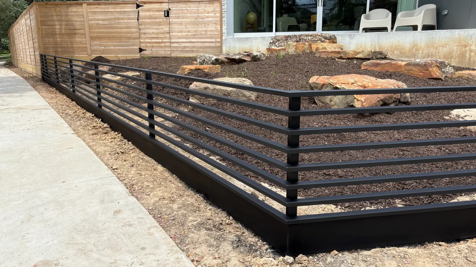 2201 Dryden residence in Houston: horizontal-bar steel fence with an integrated landscape retaining system