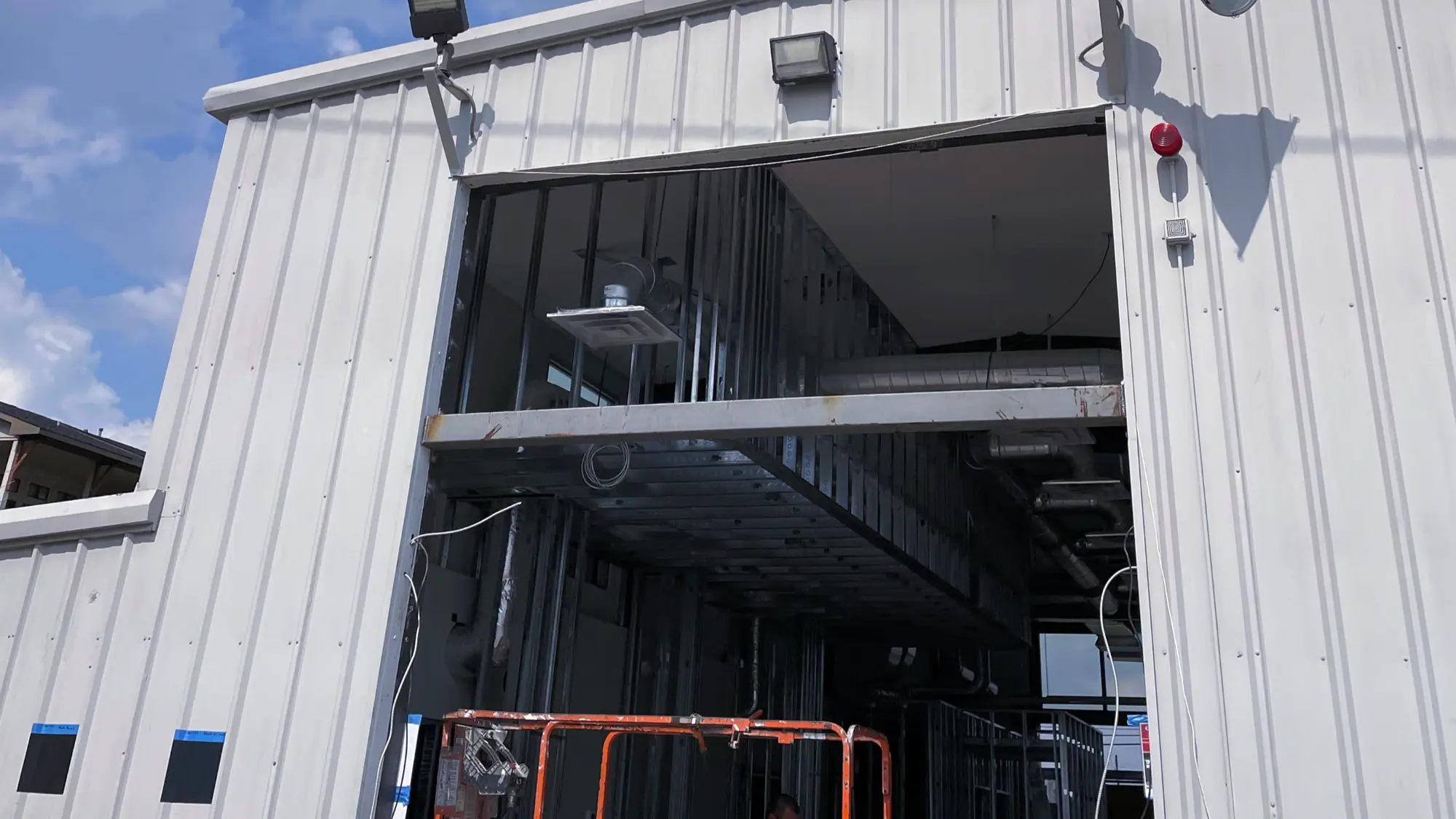 Metal building shell with a large framed opening and interior steel framing during construction