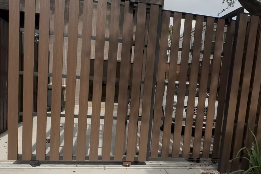 Steel-framed driveway gate with closely spaced vertical slats screening the drive behind it
