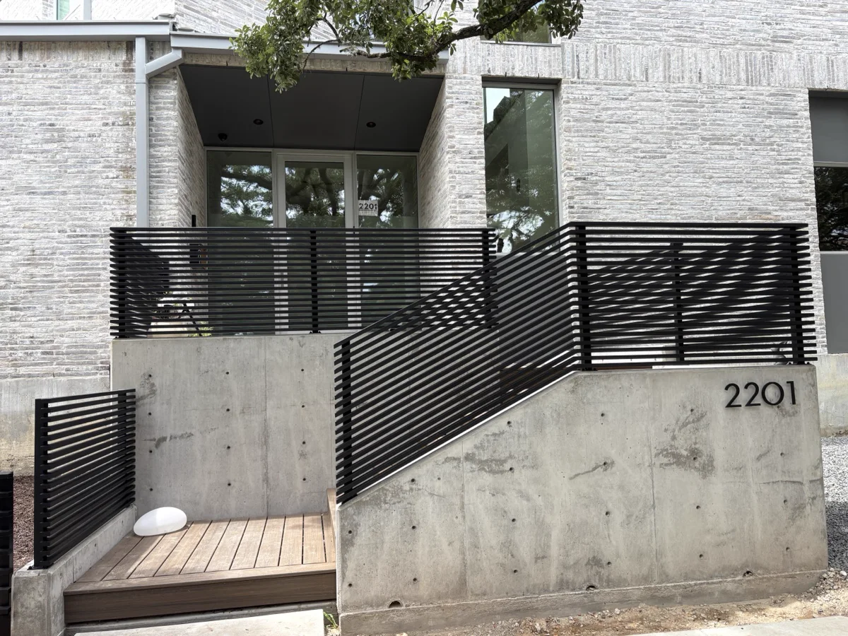 Raked steel guardrail with horizontal bars running alongside a concrete stair