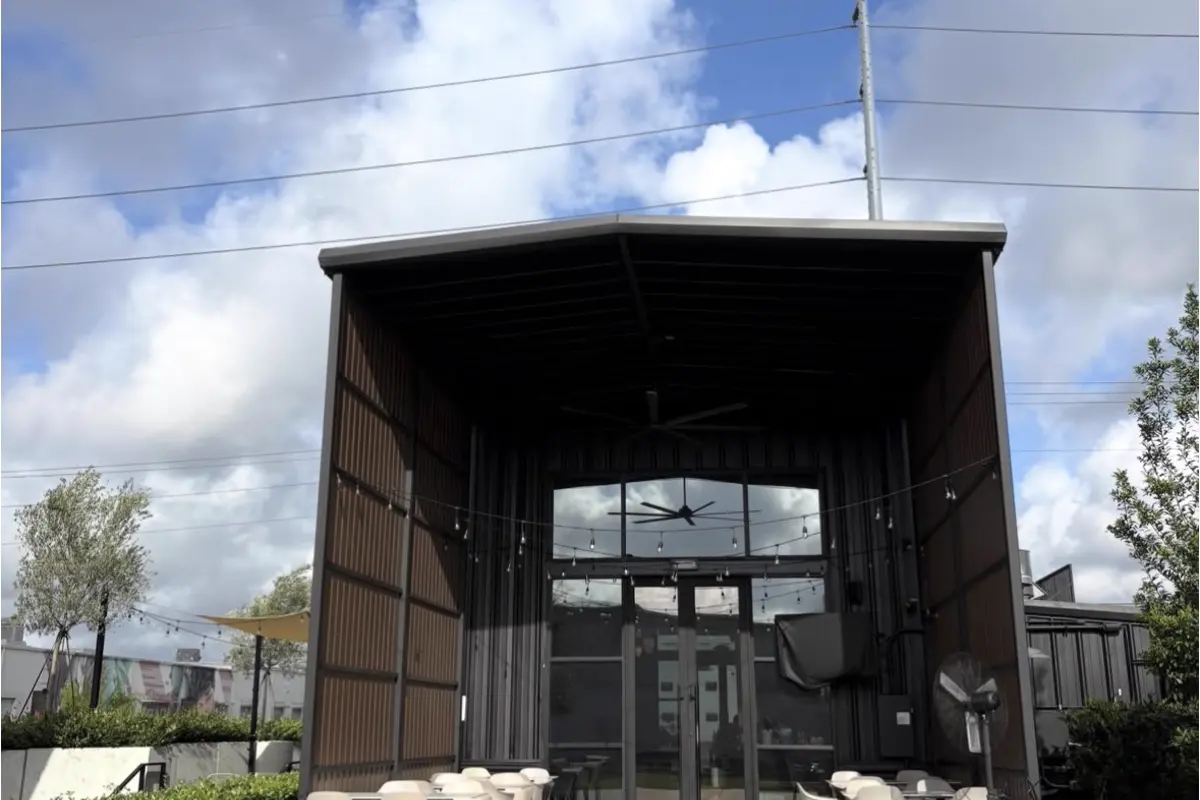 Steel-framed covered pavilion with an open canopy over a patio seating area
